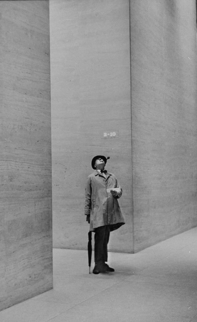 #20 French actor Jacques Tati looked at the high ceiling of a New York City lobby, 1958.
