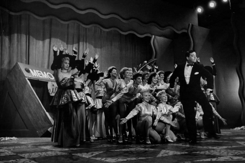 #27 Entertainer Jackie Gleason (C) executing his famous How Aweet It Is dance wlhile the chorus girls are taking a bow behind him, 1953.