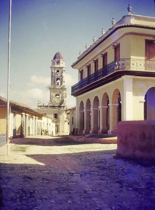#9 Clock tower with bell on a cobblestone street, 1950
