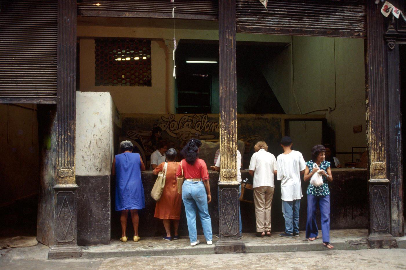 #38 Cuban men and women queuing in front of a public shop using the ration book in Cuba, 1990.