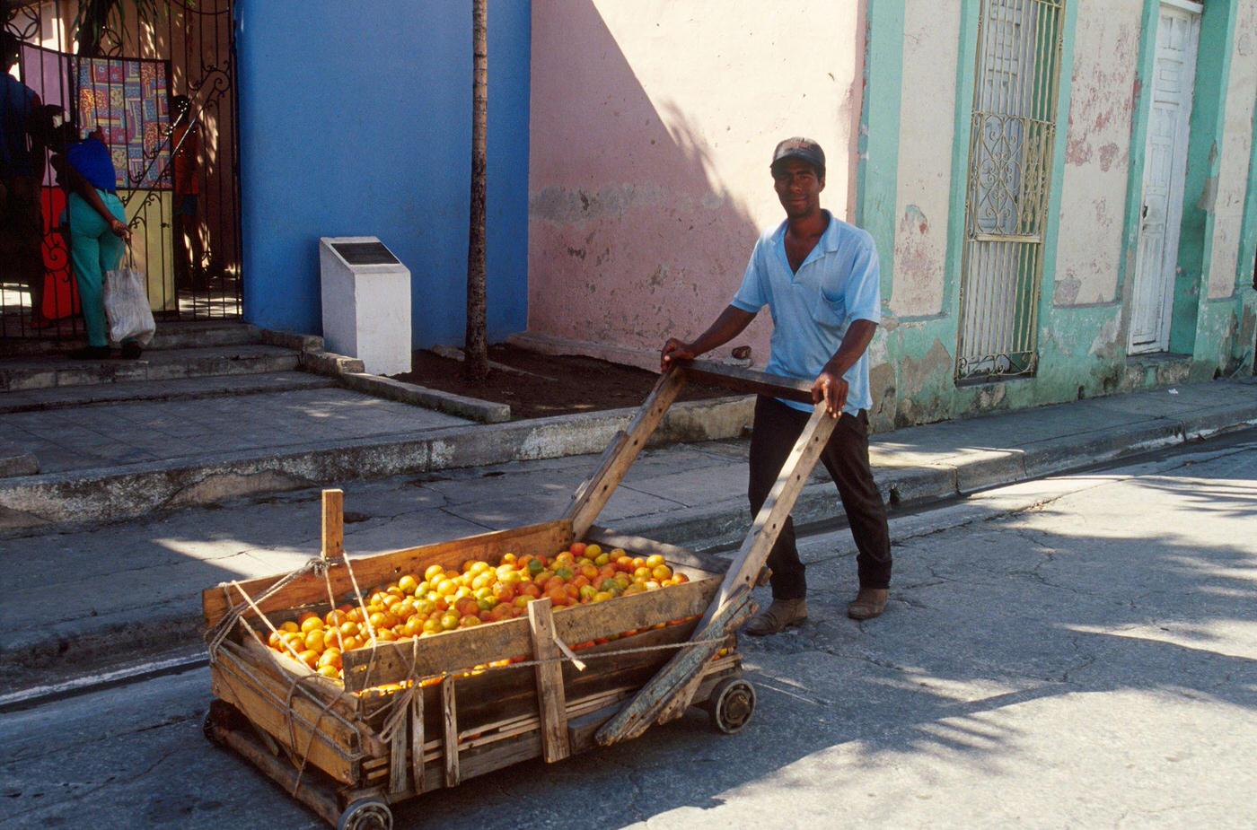 #48 Cuban man carrying oranges on a cart, Cuba, 1990.