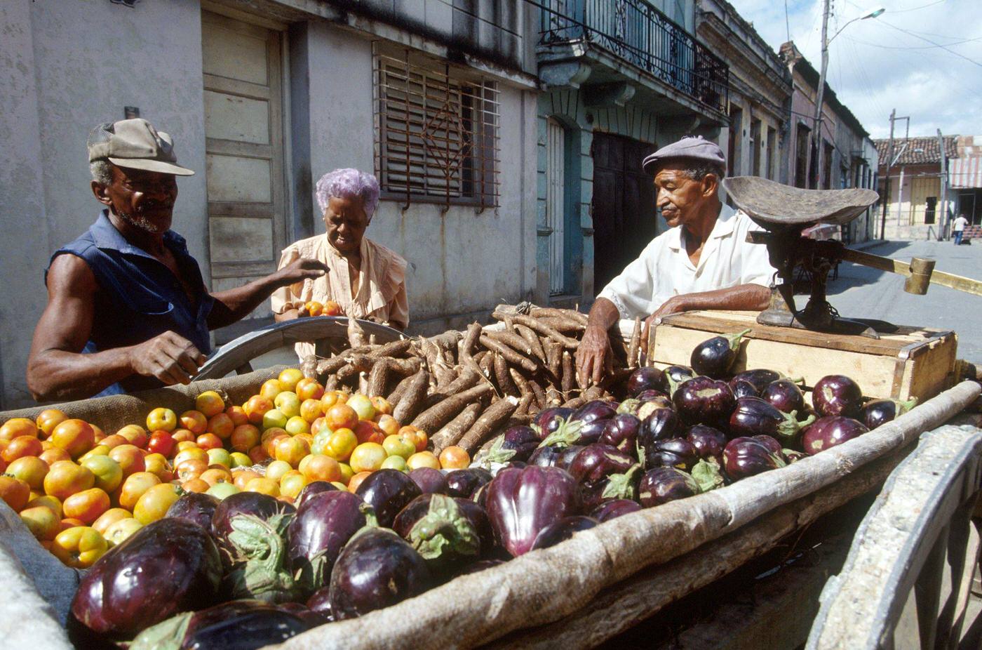 #50 Cuban man selling fruits and vegetables displayed on a cart, Cuba, 1990.