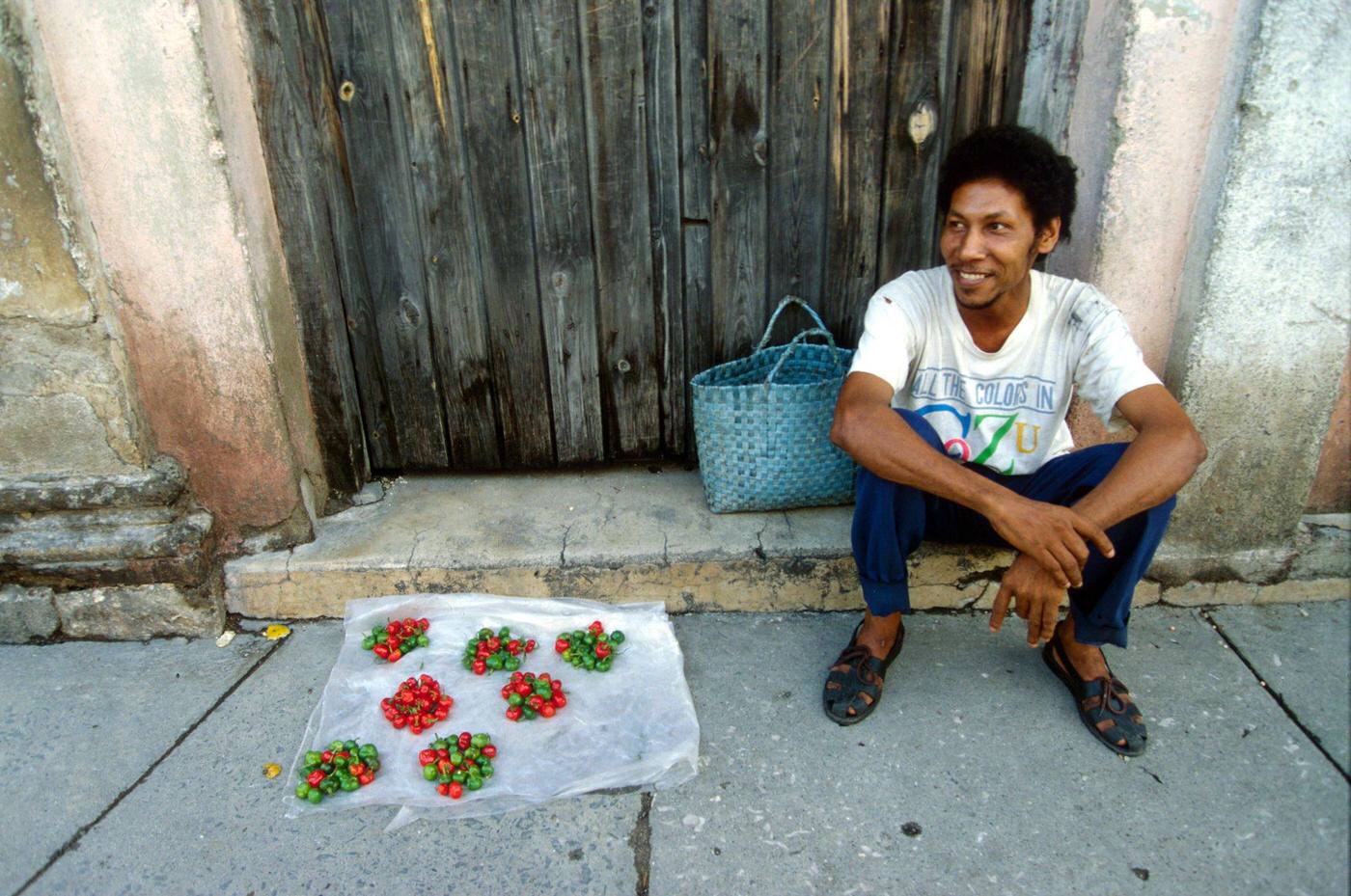 #2 Cuban man selling chili peppers displayed on the pavement in the street, Cuba, 1990.