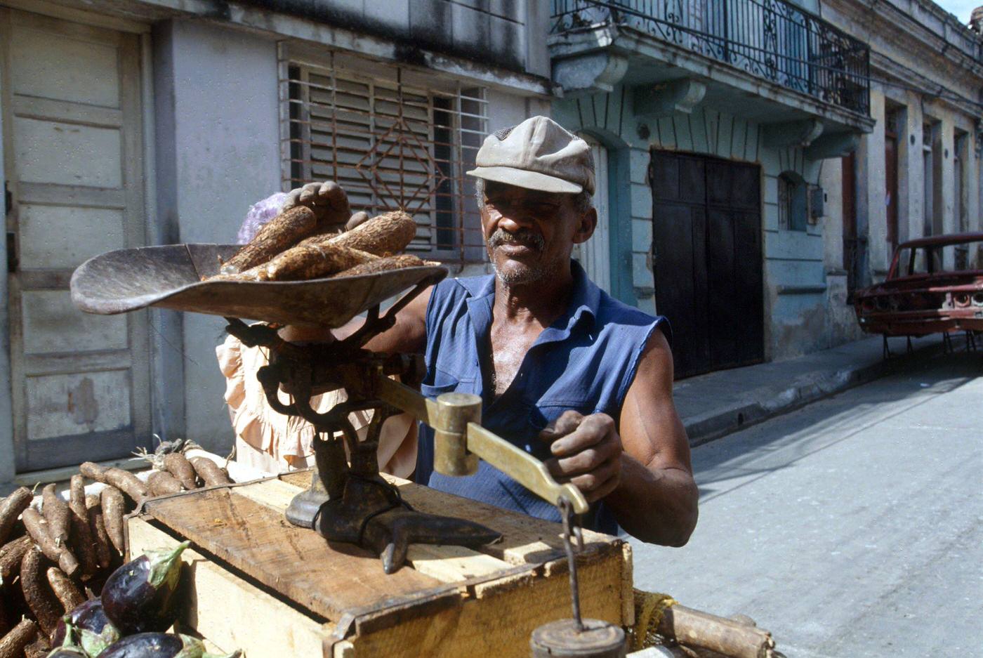 #3 Cuban man weighing yucca to sell in the street on a scale, Cuba, 1990.