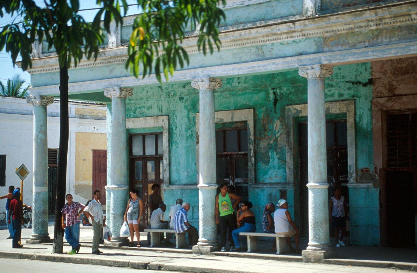 #8 Cuban men and women standing under the arcade of a building in Cienfuegos, Cuba, 1990s.