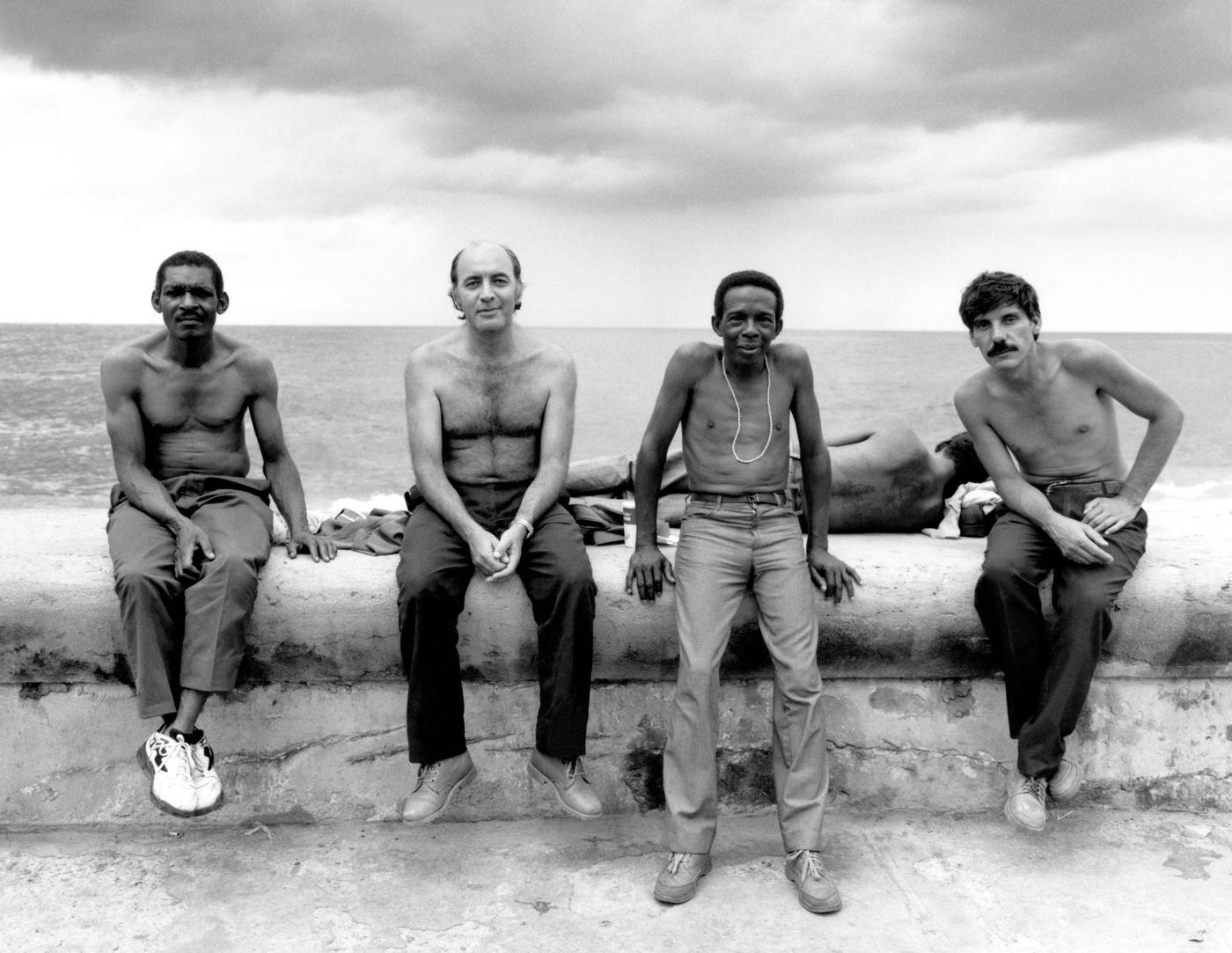 #79 General view of four shirtless men posing for a portrait while sitting on a wall in Havana, Cuba, 1996.