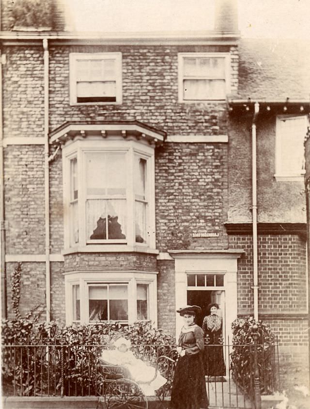 #10 An Edwardian lady with a baby in a pram stand on the pavement outside