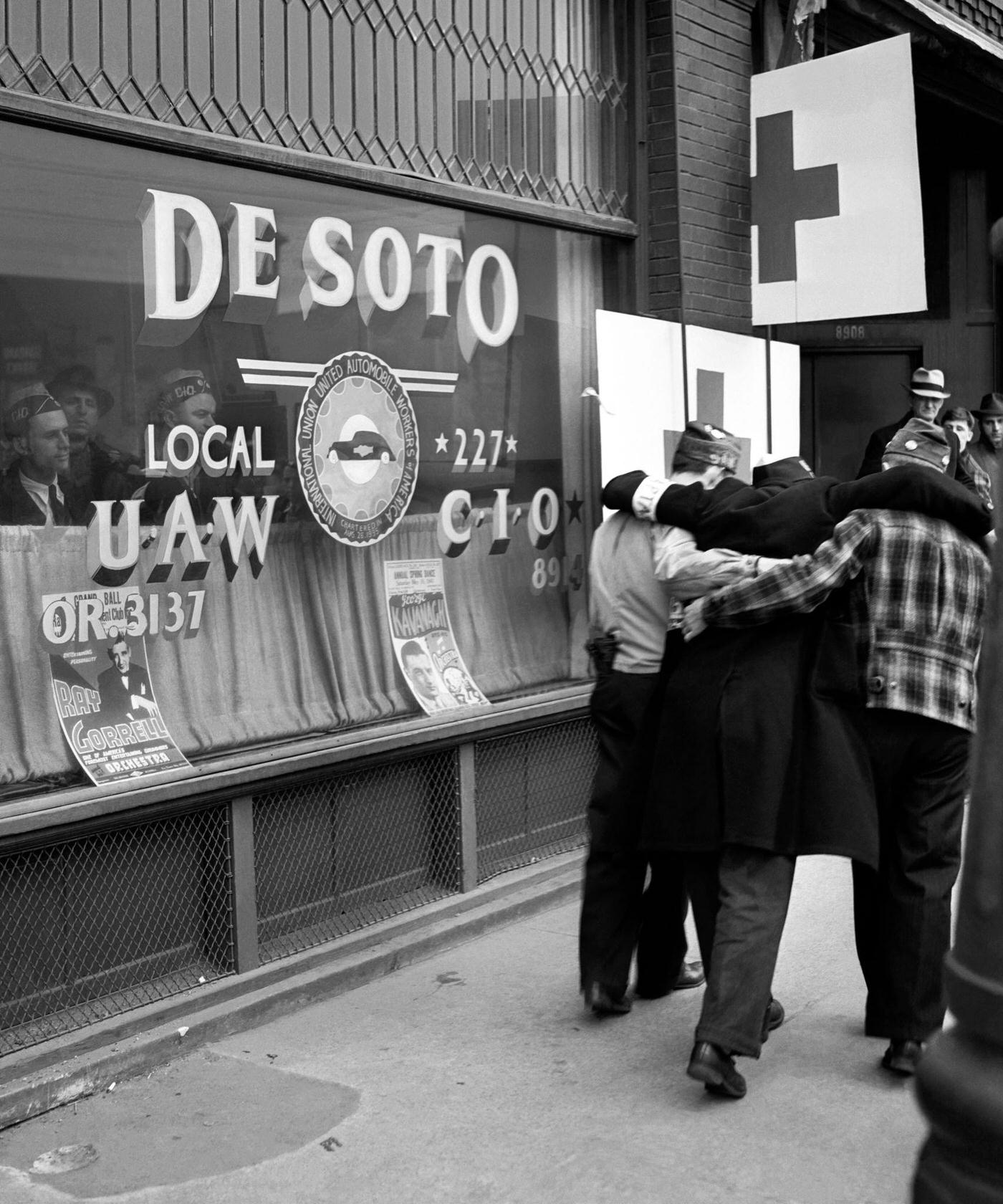 #6 Two men carry a victim into the De Soto local United Auto Workers (UAW) headquarters after being injured during the riots over the labor dispute at the Ford River Rouge complex in Dearborn, Michigan, April 1941.