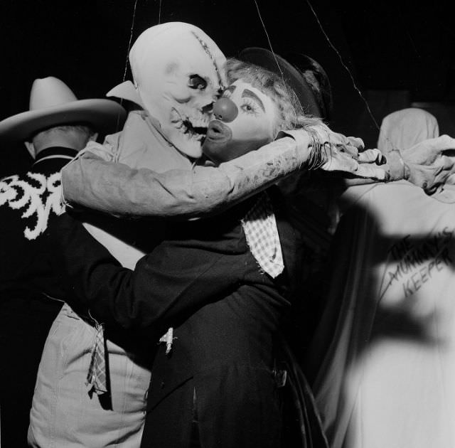 #9 A ghoulish goblin and a painted clown embrace at a Halloween party in 1955.