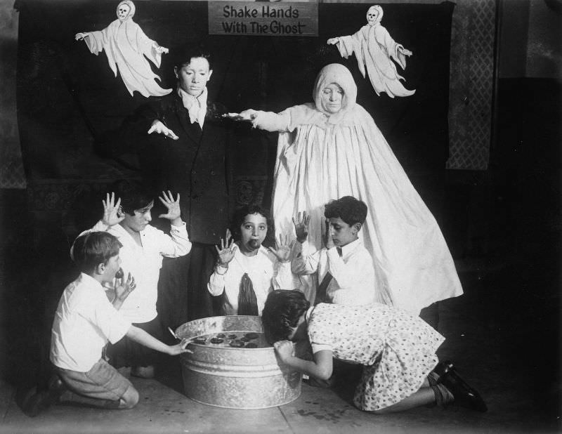#7 Children surrounded by ghosts go bobbing for apples at a Halloween party around 1935.