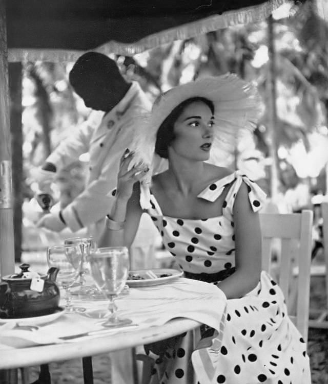 #33 Marilyn Ambrose in sun-dress of white cotton poplin with navy blue coin dots by L’Aiglon, at the British Colonial Hotel at Nassau, Harper’s Bazaar, 1948.