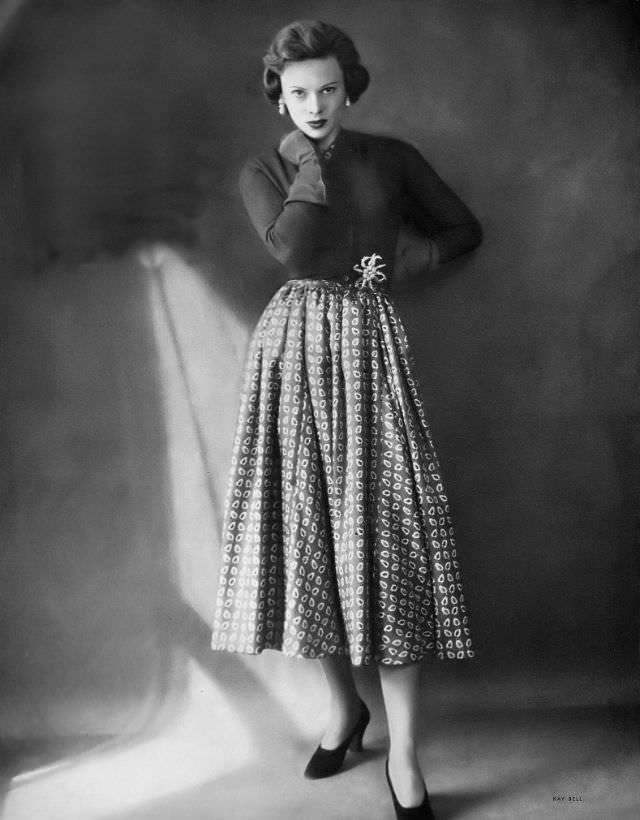 #35 Meg Mundy in ruby red cashmere cardigan cut at the waist with ruby and green tie silk dress beneath by Mainbocher, flexible jeweled starfish by Jean Schlumberger, Harper’s Bazaar, 1948.