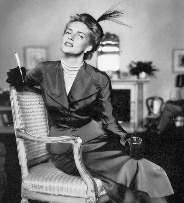 #45 Model in plum colored faille two-piece with winged lapels and skirt with loose wrap-around panel by Paul Parnes, Harper’s Bazaar, 1949.