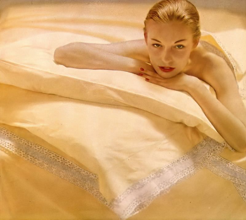 #1 Liz Pringle lying on sheets the color of daffodils in Bates percale, pillowcases and blanket embroidered in white eyelet, by Carlin Comforts, Harper’s Bazaar, October 1948