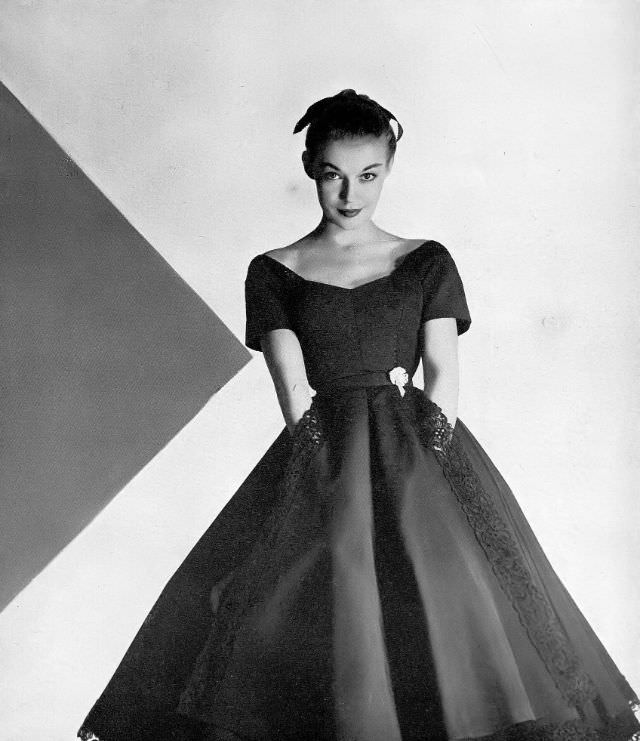 #13 Liz Pringle in black silk bengaline dress scrolled with heavy black cotton lace at neck, hem and apron front, by Omar Kiam for Ben Reig, Harper’s Bazaar, December 1951
