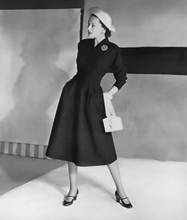 #16 Meg Mundy in a city-black waffle-piqué coat-dress by Mildred Orrick, straw harlequin-shaped hat, white calf bag by Bienen-Davis, all at Bergdorf Goodman, Vogue, April 15, 1947