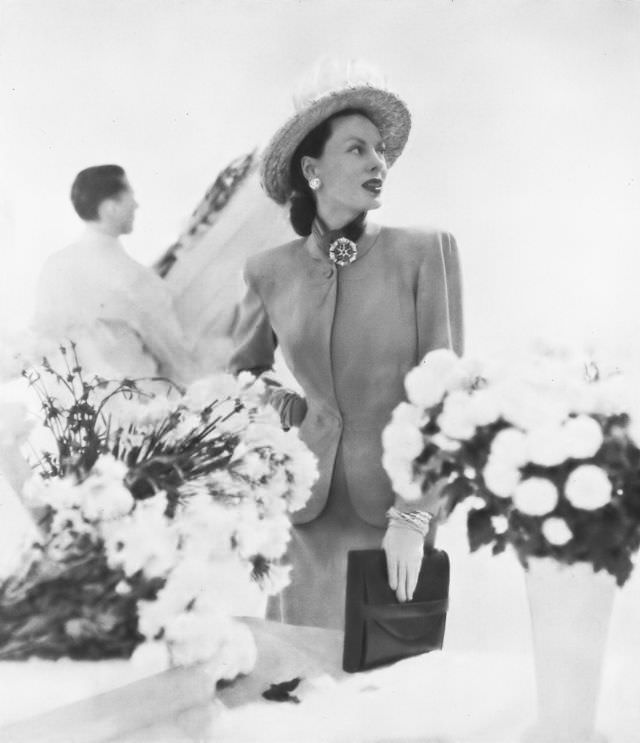 #30 Meg Mundy in pale putty-beige, worsted twill suit by Rauch for Carolyn Modes, a natural pale straw sailor by Sally Victor, jewelry by John Rubel, Vogue, March 1, 1947