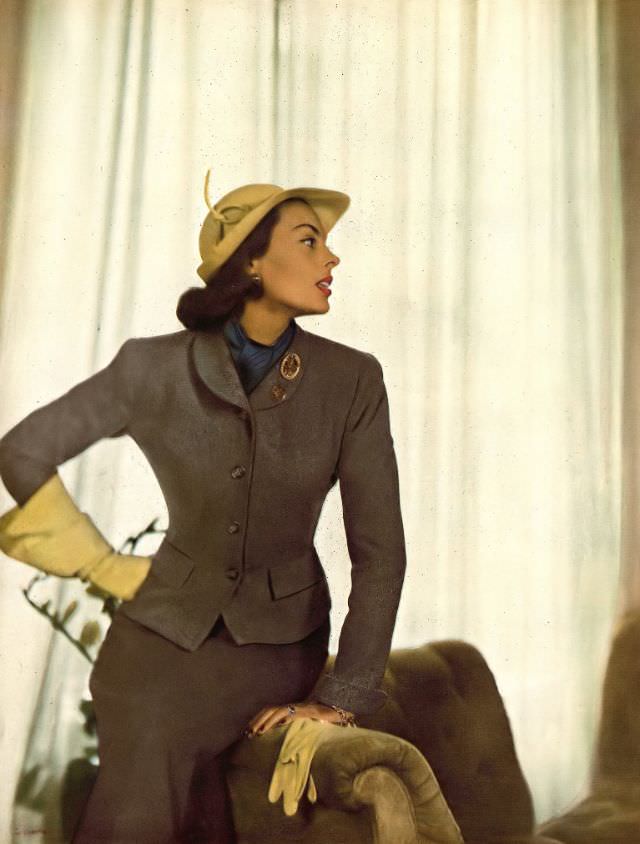#33 Meg Mundy in two-toned Hockanum flannel suit, the darker skirt is flared, by Roxspun, citron yellow gloves and hat by Lilly Daché, lapel coins by Shapiro, Harper’s Bazaar, September 1947