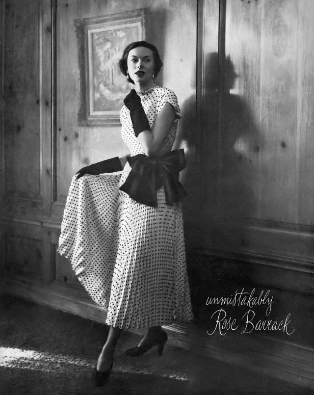 #38 Meg Mundy in black dotted silk dress entirely covered with sequins, with full pleated skirt tied at the waist in large black bow, by Rose Barrack, Harper’s Bazaar, February 1948