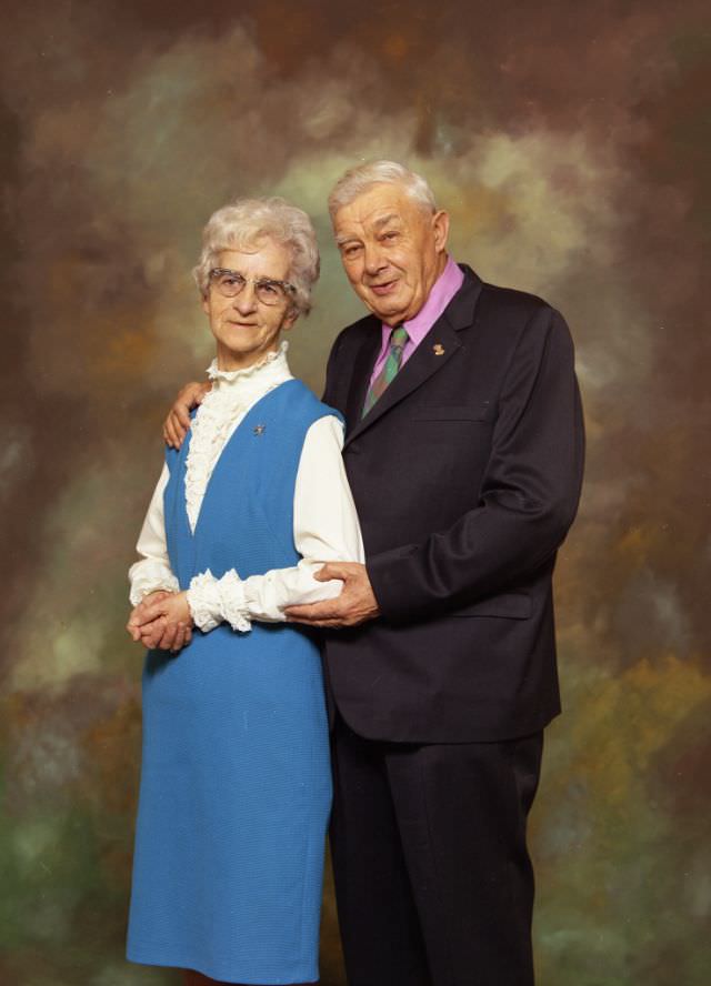 #10 Portrait of Mr and Mrs Albert Miller. Mrs Smith is on the left and is wearing a blue dress over a high-necked white top. Mr Smith is on the right and is wearing a dark suit over a pink shirt and patterned tie, November 23, 1971
