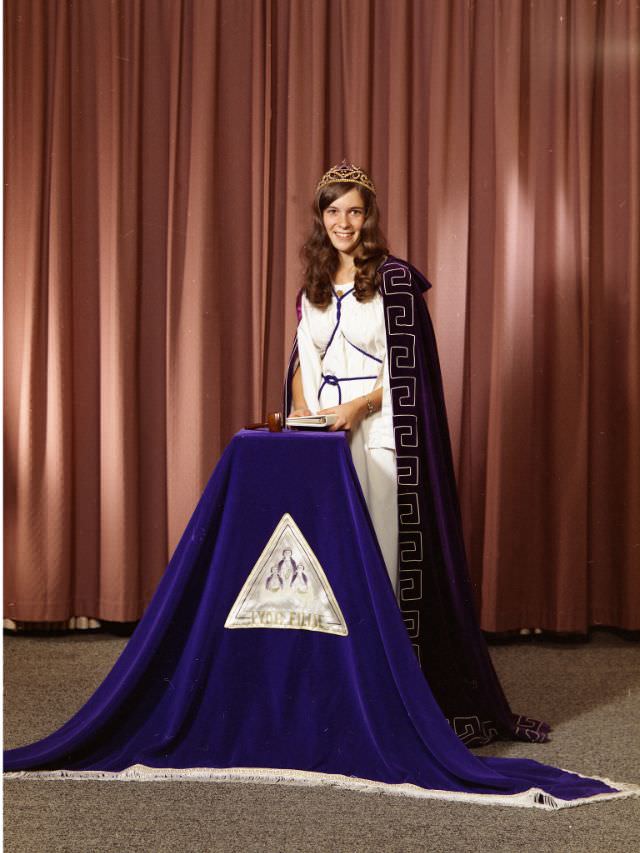 #17 Linda Barber in ceremonial Masonic dress. She is wearing a tiara, a white dress, and a dark purple cape, September 28, 1973