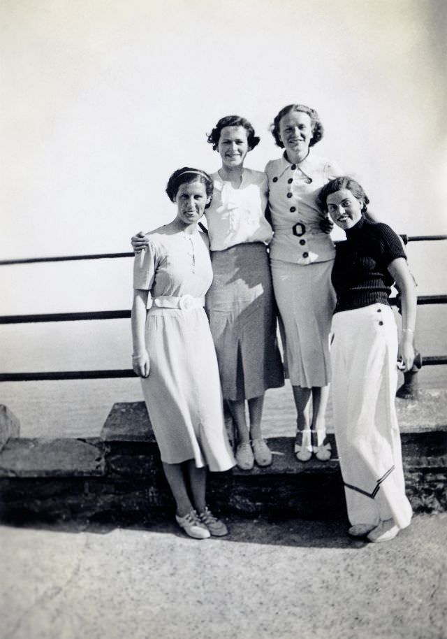 #15 A company of four well-to-do ladies posing on a promenade overlooking the sea.