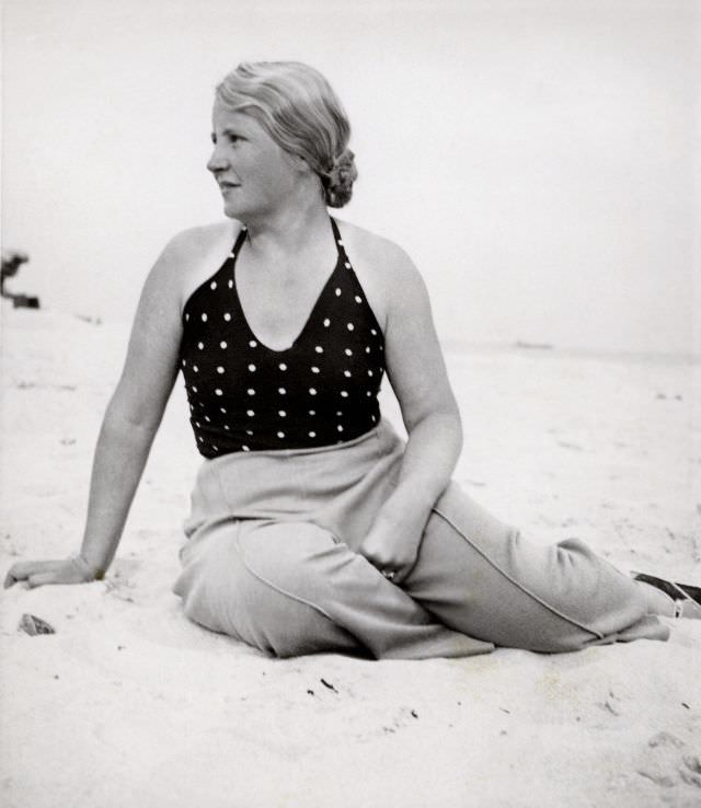 #17 A blonde lady posing on a beach in summertime. She is wearing a polka dot top and slacks with sewn-in creases, 1938