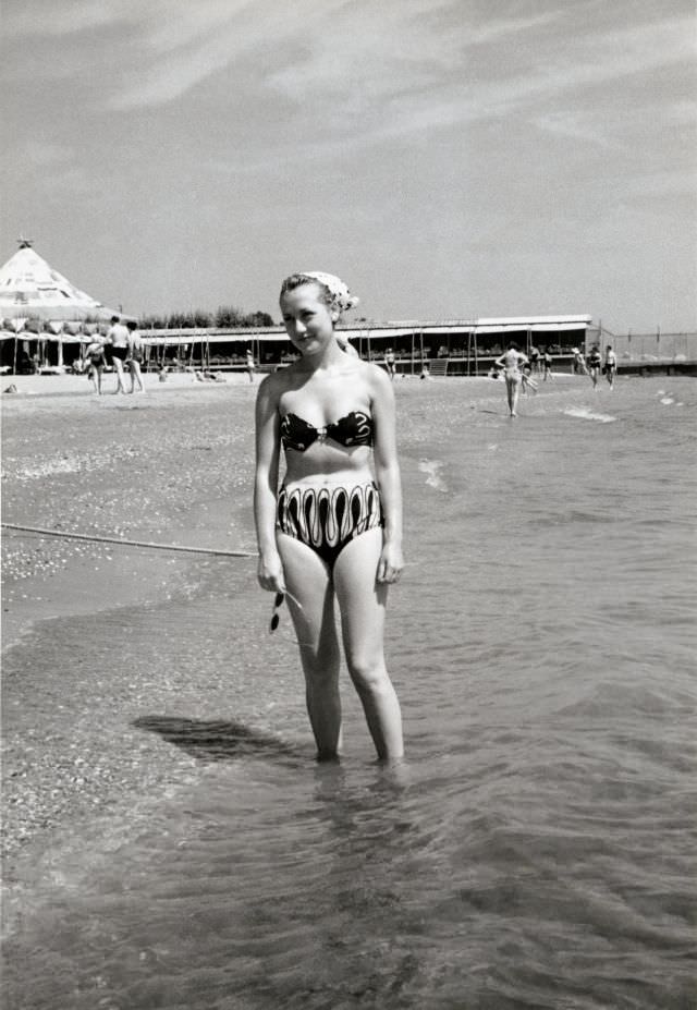 #34 A blonde lady in a two-piece swimsuit posing on a sunny beach, 1950s