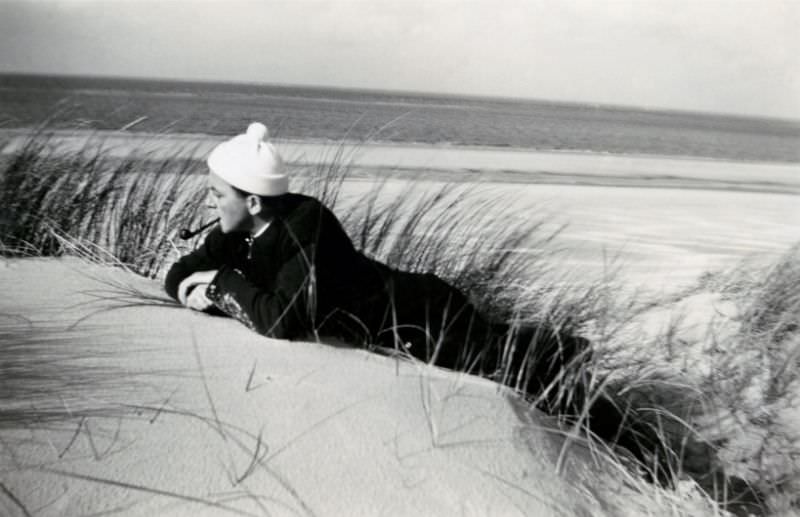 #36 A dapper, pipe-smoking fellow posing in the dunes at the seaside, 1950s