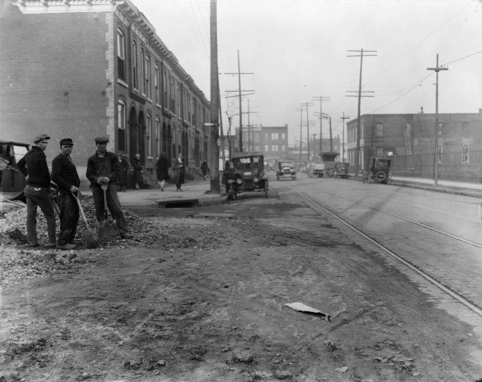 #52 Street crew posing for camera holding shovels near a pile of rubble at the intersection of Evans Avenue and North Sarah Street, 1925