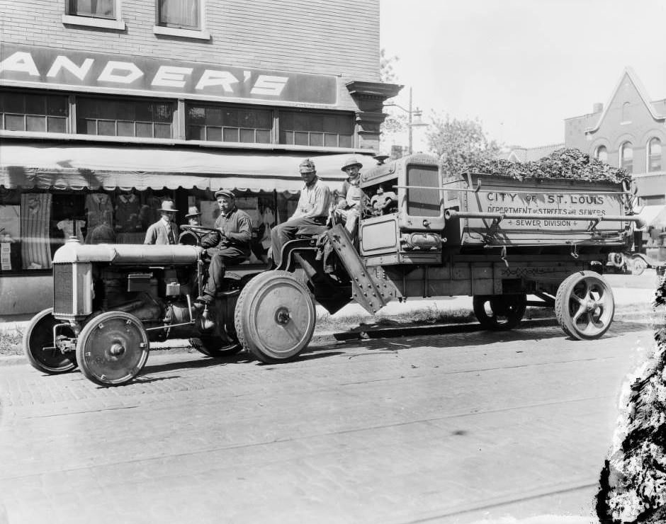 #56 View of a City of St. Louis, Department of Streets and Sewers, Sewer Division tractor and refuse truck and crew on South 39th Street, in front of Rheinlander’s Dry Goods store, 1925