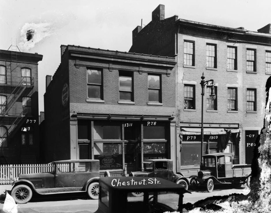 #203 Vehicles and brick storefronts on the north side of the 1300 block of Chestnut Street in downtown St. Louis in 1927. Durlacque Mfg. Co. was at 1311 at the time, 1927