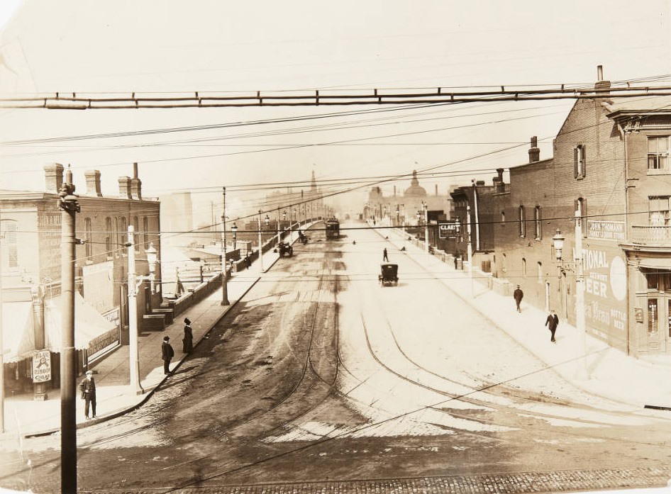#12 12th Street viaduct looking north from Chouteau Avenue, with storefronts for the John Thomann liquor store and the John H. Heller drug store visible, 1920