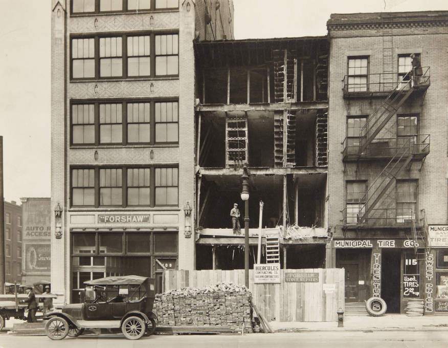 #102 Row of buildings on the 100 block of N. 12th Street with Forshaw Stove Repairs having its exterior wall replaced and Municipal Tire Co. storefront, 1920