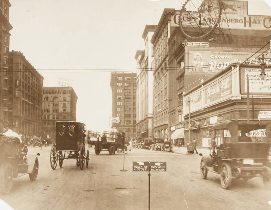 #110 12th and Locust Street, looking north with numerous cars and delivery trucks in traffic and parked along the street, 1920