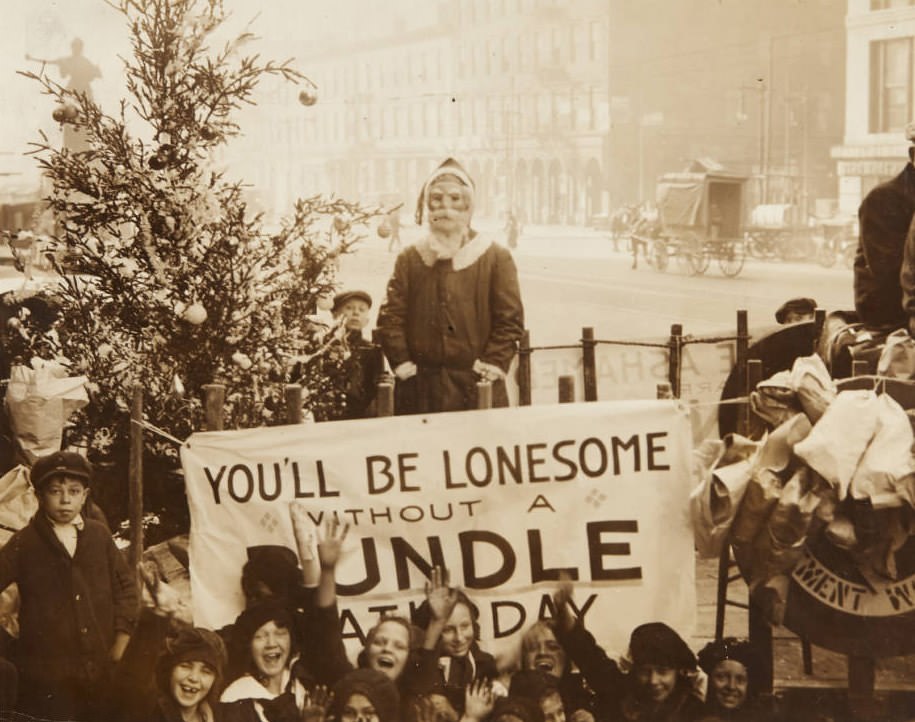 #112 Group of children gathered around a Christmas tree and a man dressed as Santa Claus on downtown street, 1920