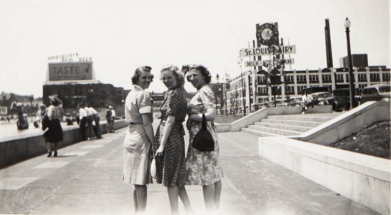 #166 Women posing for a picture near Aloe Plaza. The St. Louis Dairy building can be seen in the background, 1940