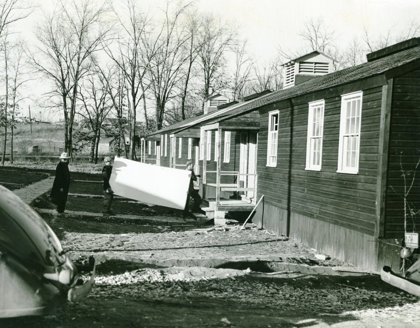 #37 Men carrying white board into a house at Jefferson Barracks, date unknown.