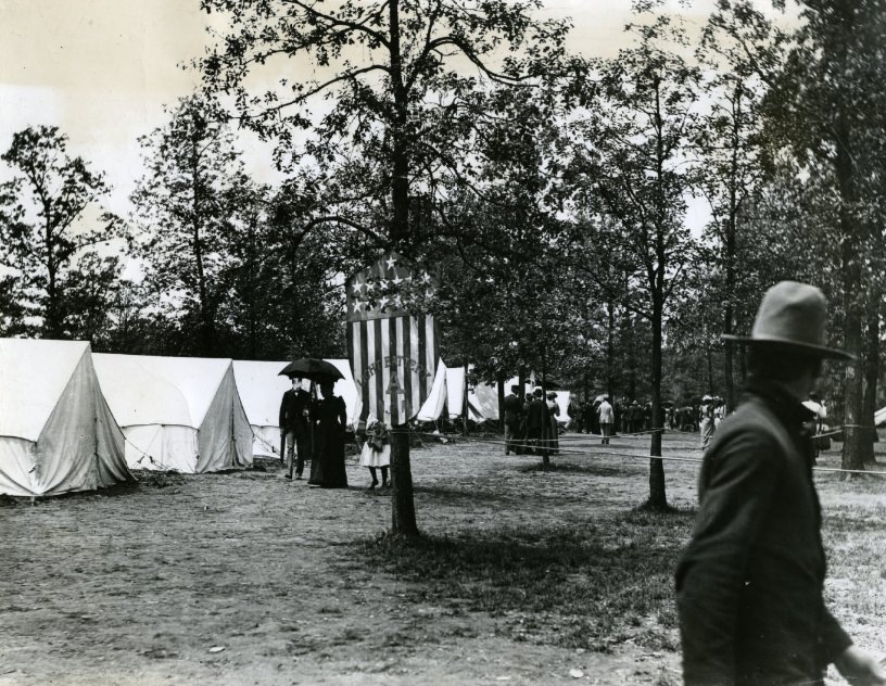 #56 Light Battery A’s camp ground with its banner hanging from a tree in Camp Stephens.