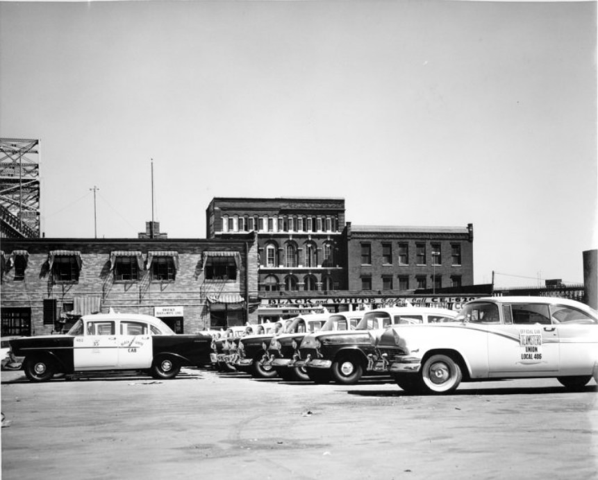 #117 Rows of taxicabs parked outside the Black and White Cab company, 1950