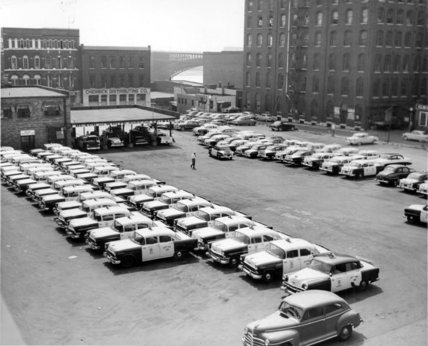 #78 Fleet of taxis parked outside the Black and White Cabs company. Eads Bridge in the background, 1956
