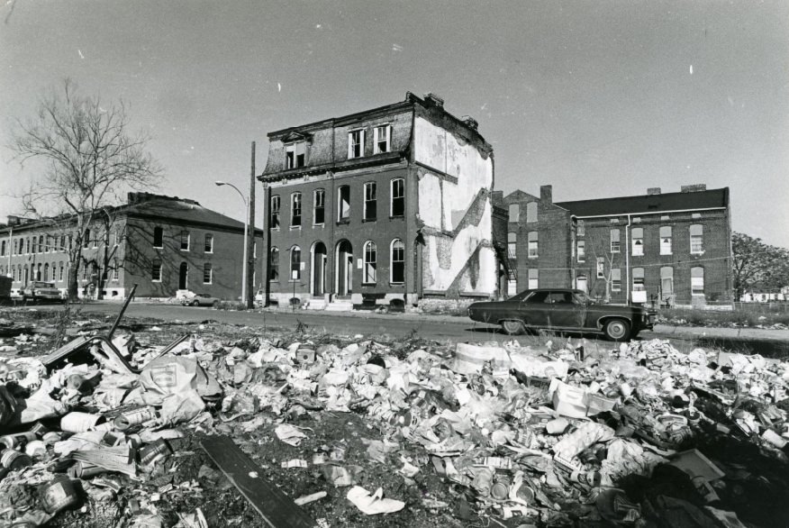 #149 At the corner of Mills and N. Leffingwell a deteriorated, abandoned building sits across from a pile of debris and junk, 1973