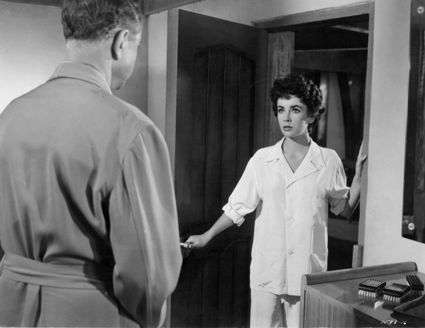 William Powell and Elizabeth Taylor in pajamas by an open door in a scene from ‘Girl Who Had Everything’ (1953).