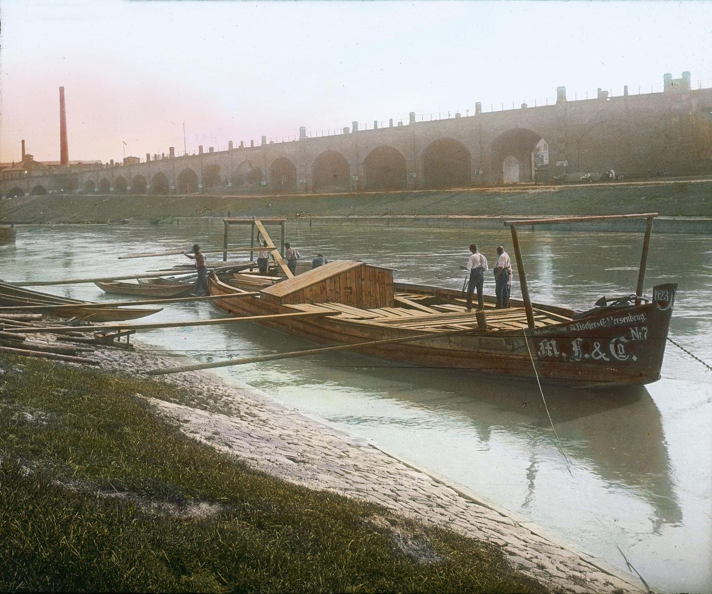 #55 Unloading lumber from a barge at the Brigittenauer Laende, with a view of the Viennese Stadtbahn on the opposite bank, 1905.