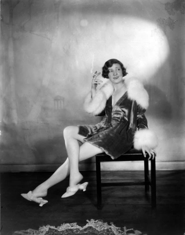 #17 Actress Margaret Campbell, wearing a fur-trimmed outfit with matching slippers, smoking a cigarette, 1928.