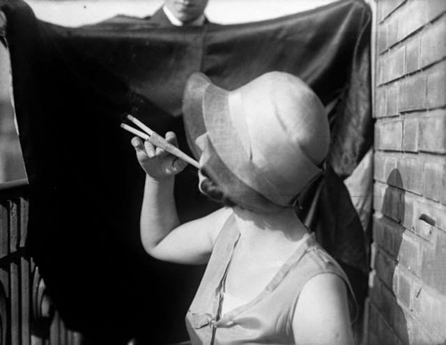 #1 A woman smoking two cigarettes simultaneously with an elegant cocktail cigaratte holder, 1929