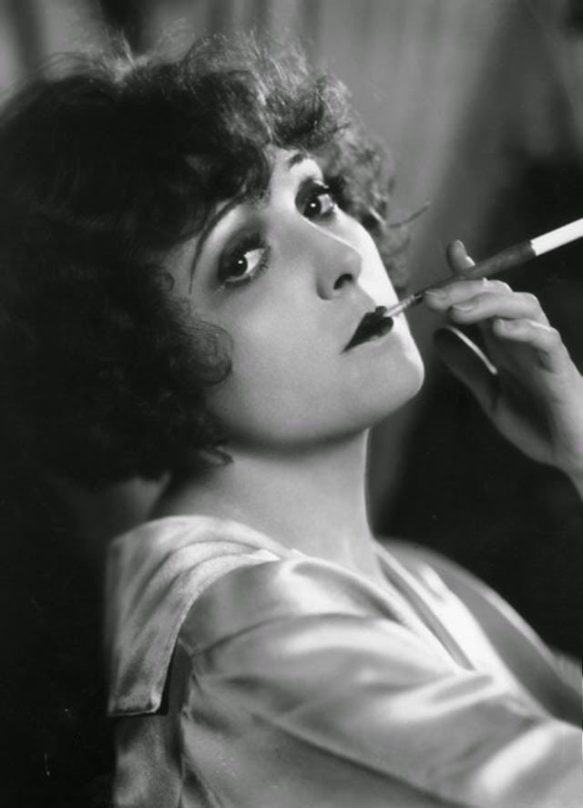#10 Madge Bellamy, the stage name of Margaret Philpott (1899–1990) the American general purpose actress of the 20s. She was a former dancer and beauty queen. Pictured in languid pose, smoking a cigarette, using a long cigarette holder, 1920