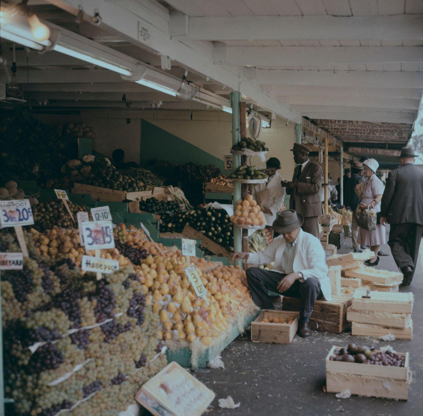#89 Customers are served by a stallholder at a fruit market near City Hall in the center of the city of Cape Town, 1965