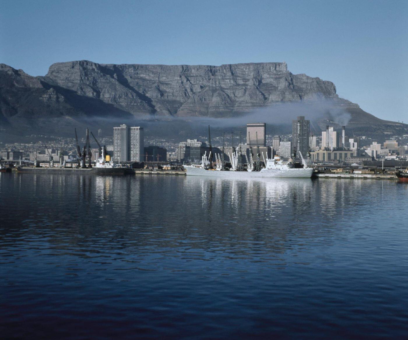 #90 Cargo ships moored in the harbor of the Port of Cape Town below Table Mountain in the city of Cape Town, 1965