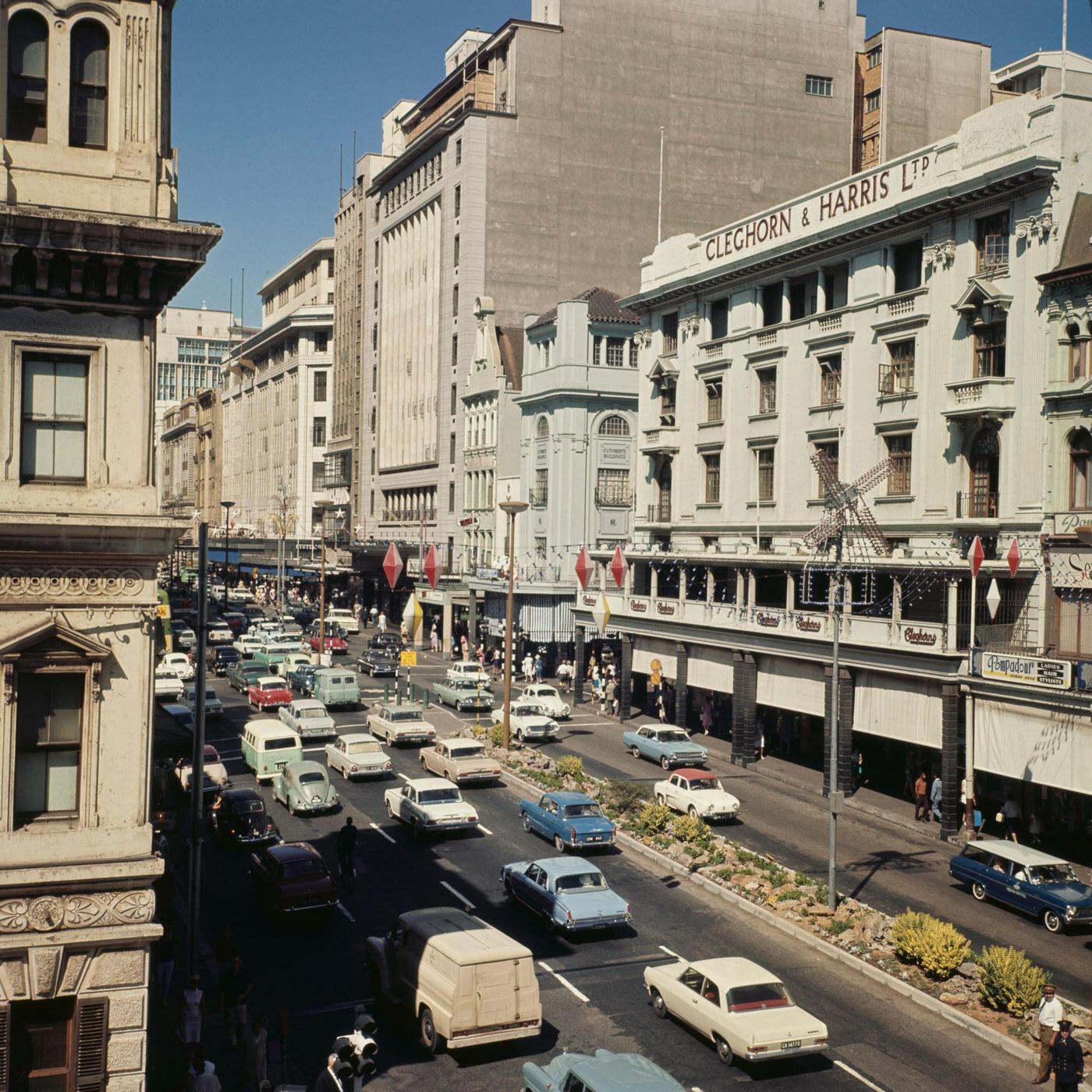 #92 Pedestrians and traffic pass the Cleghorn & Harris department store on Adderley Street in the centre of the city of Cape Town, 1966
